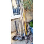 A quantity of long handled tools, rakes, pick axe and others.