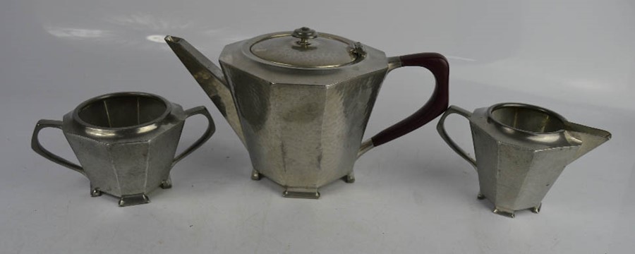 A pewter Arts & Crafts tea set comprising teapot, sugar bowl and milk jug.