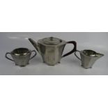 A pewter Arts & Crafts tea set comprising teapot, sugar bowl and milk jug.
