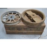 A wooden trunk with metal banding, and a vintage car wheel and pulley wheel.