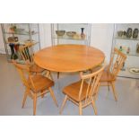 An Ercol dining table with two drop leaves, together with a set of four Ercol chairs.