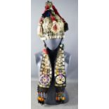 An Usbekistan ceremonial headdress adorned with metal plaques, beaded emblems, shells and other