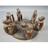 An African carved ornament depicting six figures seated around a fire pit, 16cm diameter.