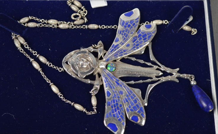 An Art Nouveau style silver and enamel dragonfly brooch with female face mask. 11.5cm high.