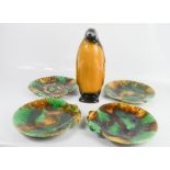A group of shell form plates, in green and brown glaze, together with a ceramic penguin.