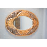 An Arts & Crafts oval oak carved wall mirror, 43 by 32cm.
