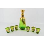 A Bohemian green glass decanter set, to include six glasses, gilded decoration and enamelled