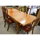 An extending walnut veneered dining table, together with a harlequin set of dining chairs with