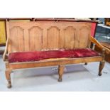 A Georgian oak settle, with a panel back, raised on short cabriole legs. A/F