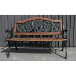 A green painted cast iron garden bench, with wooden slats, and the back depicting sunflowers.