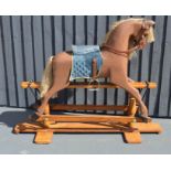 A painted rocking horse with blue saddle, raised on a pine base.