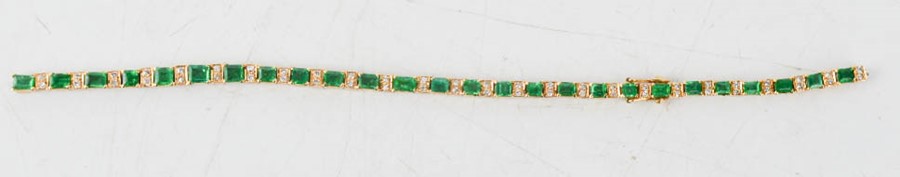 An 18ct emerald and diamond line style bracelet with trap cut emeralds, each with two diamonds