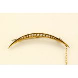 A 15ct gold and seed pearl crescent moon brooch with safety chain, 4.5cm long, 2g.