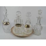 Four cut glass decanters, three with silver bottle tags, together with a silver plated wine tray.