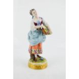 A German porcelain Volkstedt figure of a flower seller, impressed V20674 to the base, 20cm high.