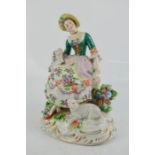 A Sitzendorf porcelain figure of a woman with dog on her lap and sheep to feet, 16cm high.