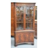 A 19th century style floor standing corner cupboard, with concave front, dentil moulded cornice