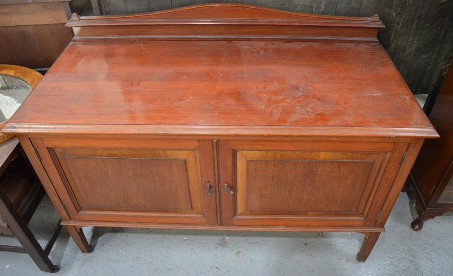 An Edwardian mahogany side board, with shaped back, and two fielded panel doors enclosing shelves,