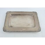 A silver rectangular dish raised on four bun feet, with scallop shells to the corners and decorative