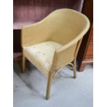 A Lloyd loom type armchair painted gold, with upholstered seat.