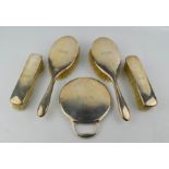 A silver dressing set, comprising a hand mirror, two clothes brushes, and two hair brushes,