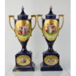 A pair of Victorian porcelain urns, with cobalt blue ground, depicting figural scenes, and having