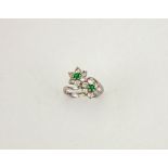 An 18ct white gold, diamond and emerald ring, in the form of a double flower, the brilliant cut