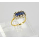 An 18ct gold, diamond and sapphire ring, set with three oval cut sapphires, bordered by diamonds,