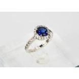 An 18ct white gold, sapphire and diamond ring, the brilliant cut 1.30ct sapphire, bordered by