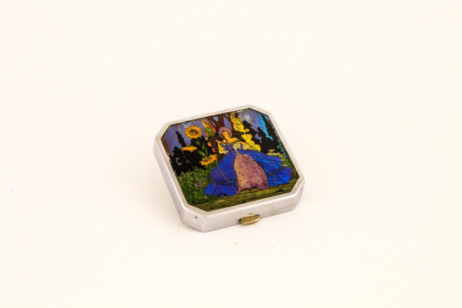 A vintage compact, depicting hand painted and butterfly wing lady amidst flowers.