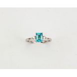 An 18ct white gold, diamond and aquamarine ring, the emerald cut 0.80ct aquamarine, flanked by two