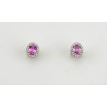 A pair of 18ct white gold, pink sapphire and diamond earrings, approx 0.50ct sapphire each, bordered