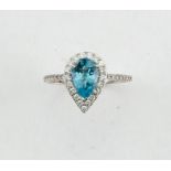 An 18ct white gold, diamond and aquamarine ring, the pear cut aquamarine approx 1ct, bordered by