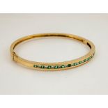 A 14ct gold, diamond and emerald bangle, the thirteen brilliant cut emeralds, interspersed with