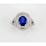 An 18ct white gold, sapphire and diamond ring, the oval cut 2ct sapphire bordered by two rows of