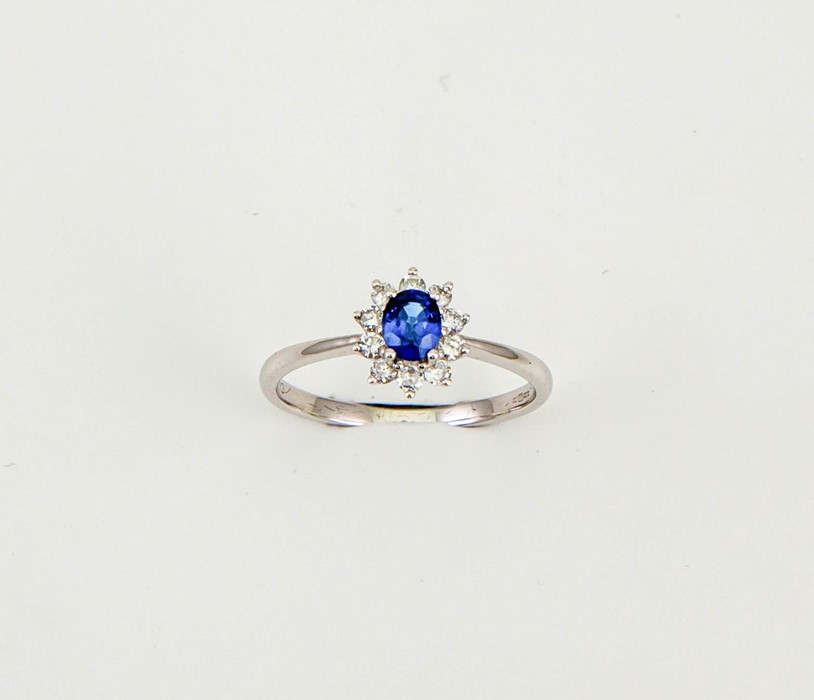 An 18ct white gold, sapphire and diamond ring, the oval cut 0.50ct sapphire bordered by 0.25ct