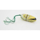 A vintage enamelled thimble and cotton holder, with green tassel, 5cm long.