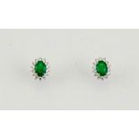 A pair of 18ct white gold, emerald and diamond earrings, the oval cut emeralds approx 0.70cts