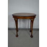 An oval top occasional table, with carved edge and raised on cabriole legs carved at the hip and