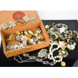 A cigar box containing costume jewellery, including brooches, necklaces, vintage cigarette rest