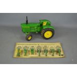 The evolution of John Deere tractors on original card by Ertl and a tin plate John Deere tractor