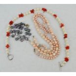 Four pearl necklaces, one grey pearl one with coral and two pink examples.