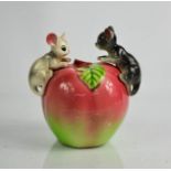 A kitch ceramic money box modelled with mice perched upon an apple, 13cm high.