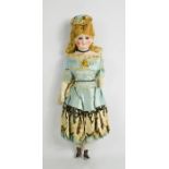 A late 19th century doll, dressed in a blue silk gown, with gilt star, lace and sequins , and silk
