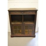 An oak cabinet, with one carved drawers, and two cupboard door below an open shelf, 117 by 107 by