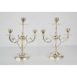 A pair of silver plated candelabra, the three candle sockets raised above a central sphere,
