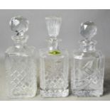 Three cut glass decanters of different form, tallest 26cm high.