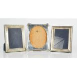 Three silver photograph frames, one embossed with decoration, the largest measures 25 by 20cm.