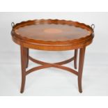 An Edwardian oval tray on stand, the wavy edge tray top with brass handles, the stand having an X-