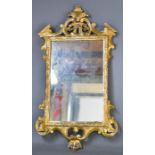 A 19th century style giltwood wall mirror, with crested top and scrollwork frame, 78 by 43cm.